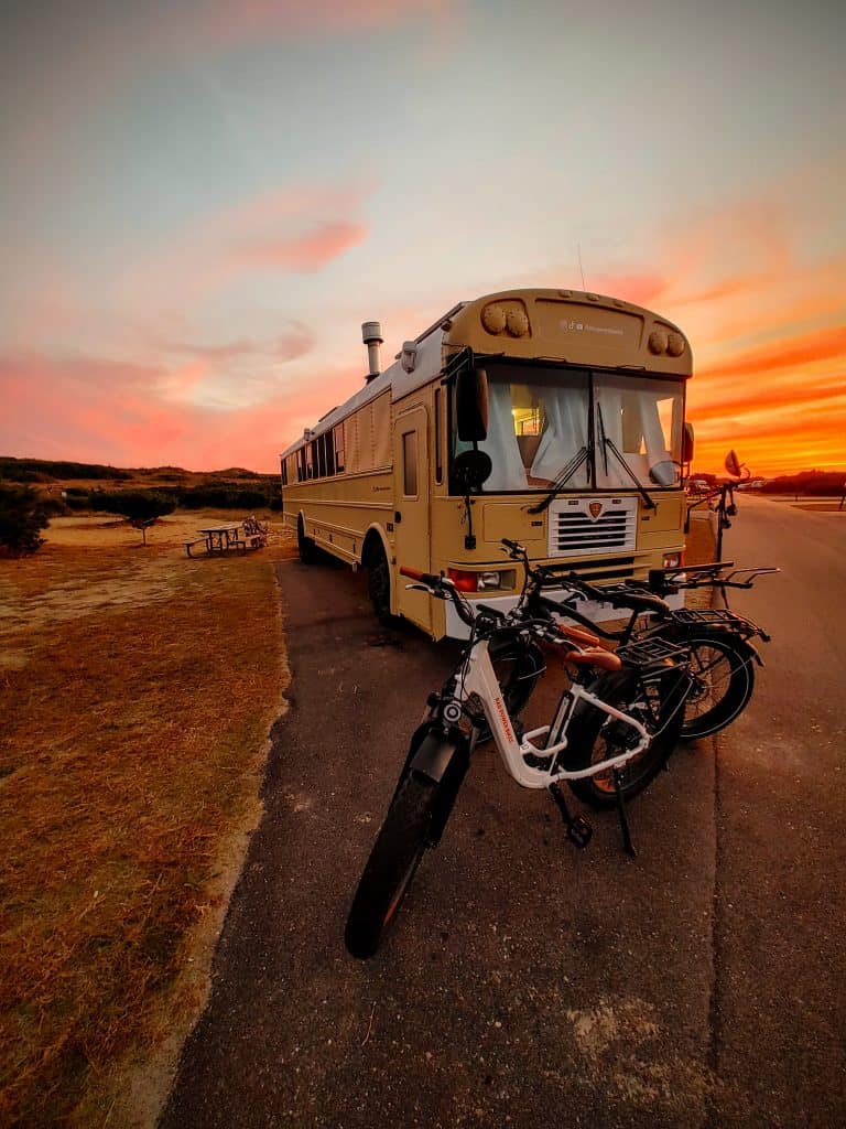 E-bikes sit in front of a skoolie at sunset | RV Today