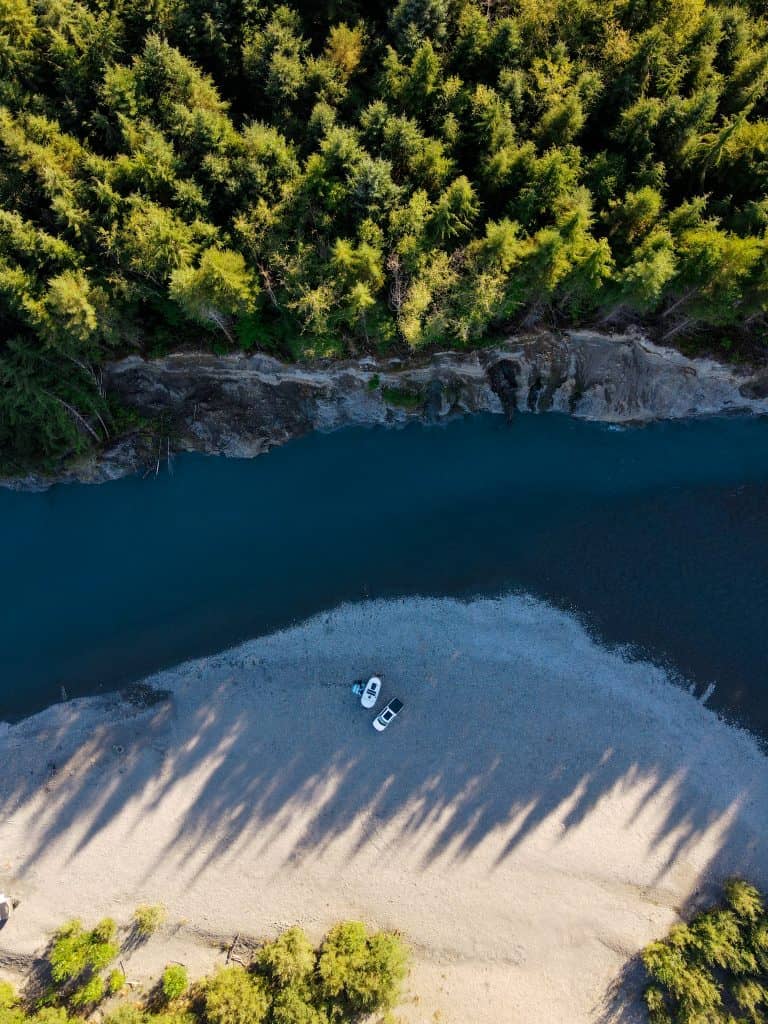 RV travel trailer and truck parked next to a river, birds eye view | RV Today